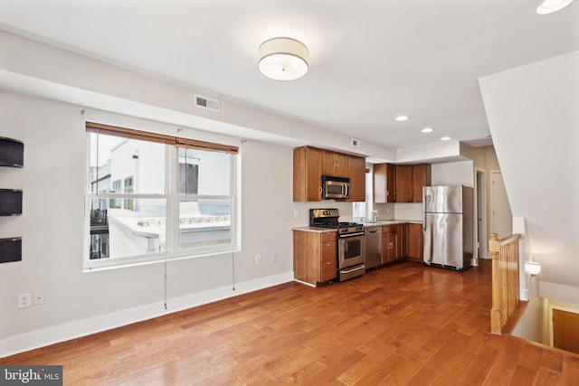 kitchen with wood finished floors, baseboards, visible vents, stainless steel appliances, and light countertops