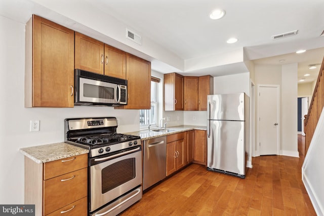 kitchen with light wood-type flooring, visible vents, appliances with stainless steel finishes, and brown cabinets