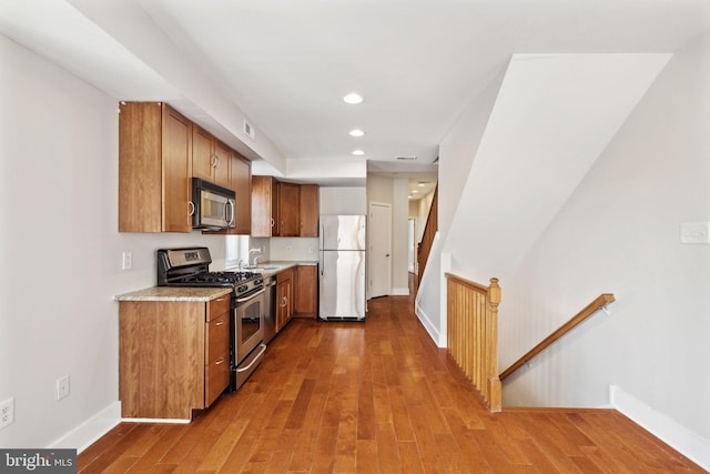 kitchen with light countertops, wood finished floors, brown cabinets, and stainless steel appliances