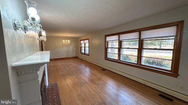 interior space with a textured ceiling, wood finished floors, visible vents, baseboards, and an inviting chandelier