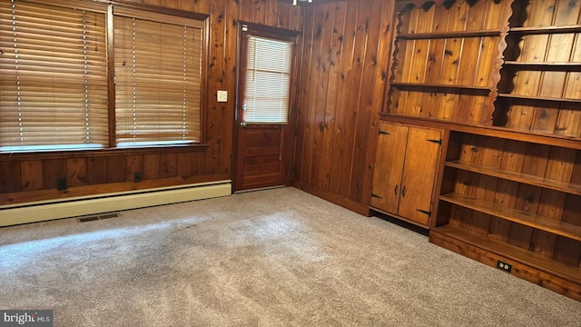 carpeted foyer with baseboard heating and wooden walls