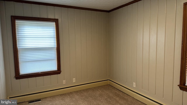 carpeted empty room with ornamental molding, a baseboard heating unit, wooden walls, and a textured ceiling