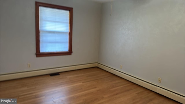 unfurnished room featuring light hardwood / wood-style flooring and a baseboard heating unit