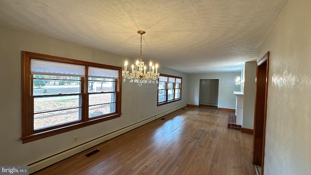 unfurnished dining area featuring a textured ceiling, a baseboard radiator, wood finished floors, and a notable chandelier