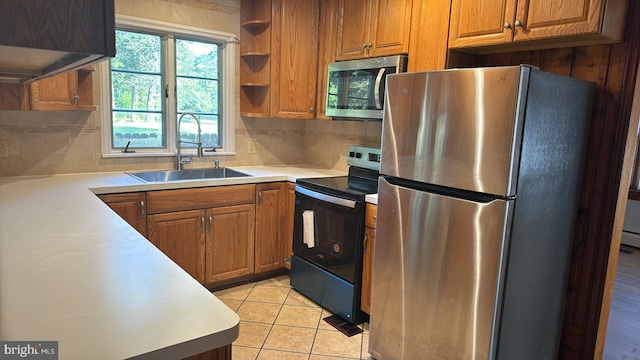 kitchen featuring a sink, light countertops, appliances with stainless steel finishes, brown cabinets, and tasteful backsplash