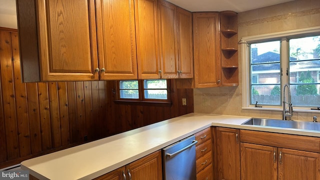 kitchen featuring brown cabinetry, a sink, and dishwasher