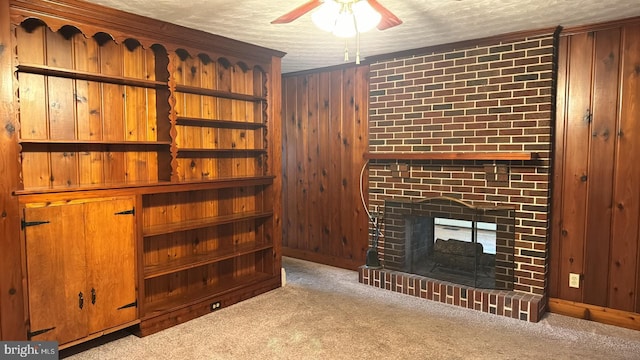 unfurnished living room with light carpet, a brick fireplace, a textured ceiling, and wooden walls