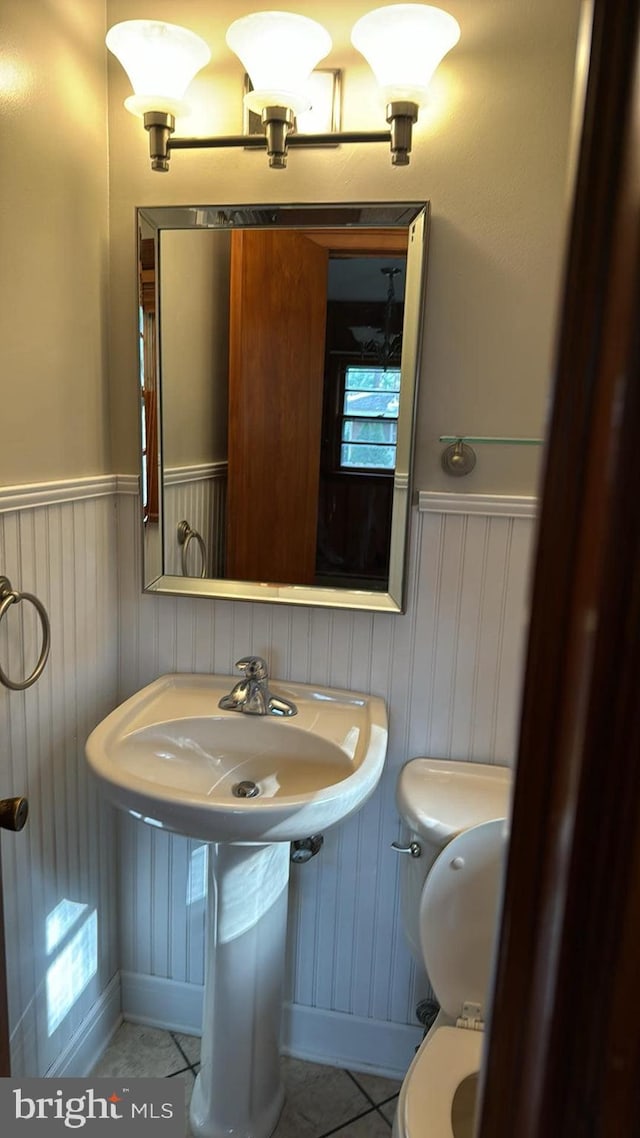 bathroom featuring wainscoting, tile patterned flooring, and toilet