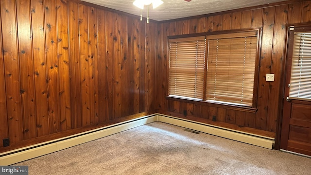 spare room with wood walls, carpet, a textured ceiling, and ceiling fan