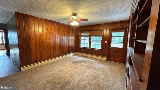 unfurnished room featuring carpet, a baseboard radiator, a ceiling fan, wooden walls, and a textured ceiling