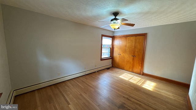 unfurnished bedroom with a baseboard radiator, ceiling fan, a textured ceiling, and light hardwood / wood-style flooring