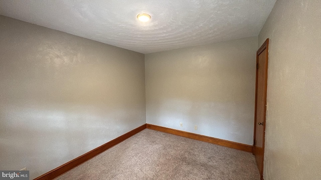 empty room featuring a textured ceiling and carpet