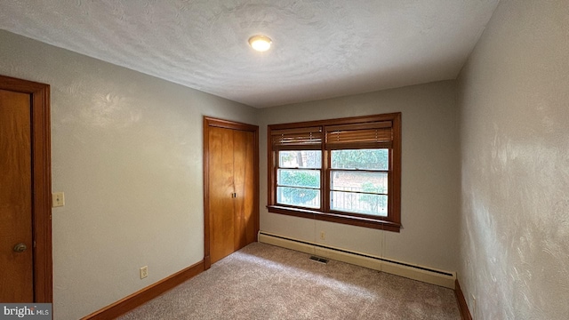 unfurnished bedroom with a closet, a textured ceiling, baseboard heating, and light colored carpet