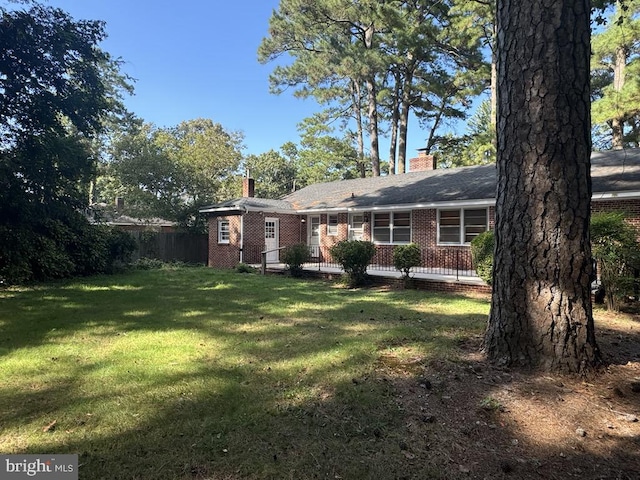 exterior space with brick siding, a chimney, and a front lawn