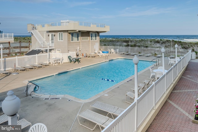 view of swimming pool featuring a patio and a water view