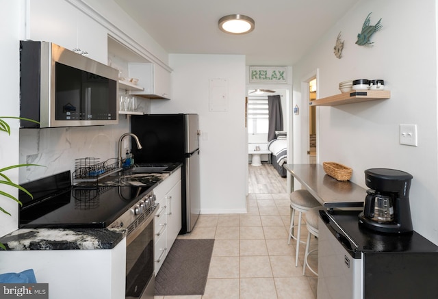 kitchen with sink, light tile patterned floors, appliances with stainless steel finishes, and white cabinetry