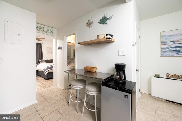 kitchen featuring a kitchen breakfast bar, light tile patterned floors, and tasteful backsplash