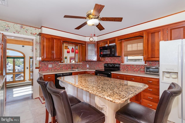 kitchen with decorative backsplash, a breakfast bar area, black appliances, sink, and a center island