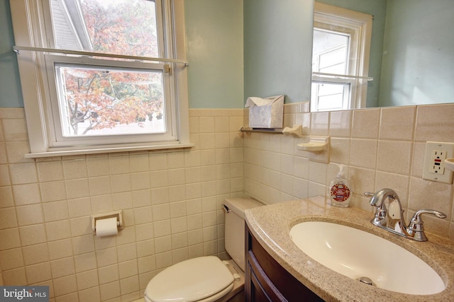 bathroom featuring vanity, plenty of natural light, toilet, and tile walls