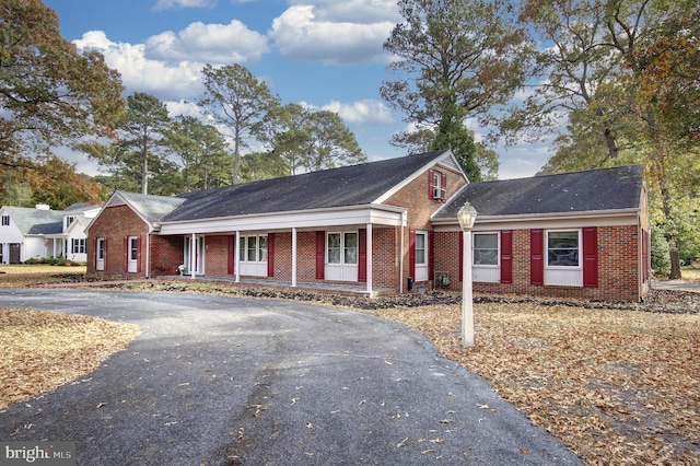 view of front of property with covered porch, driveway, and brick siding