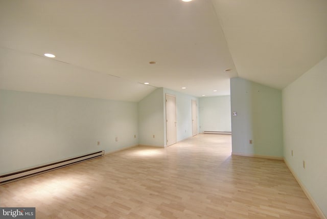 additional living space with a baseboard heating unit, lofted ceiling, and light hardwood / wood-style flooring