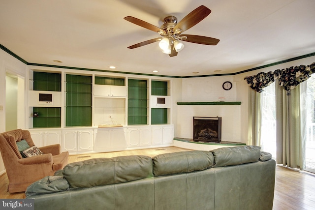 living room with crown molding, ceiling fan, and light hardwood / wood-style flooring