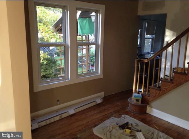 foyer entrance with a baseboard heating unit, a wealth of natural light, and hardwood / wood-style floors