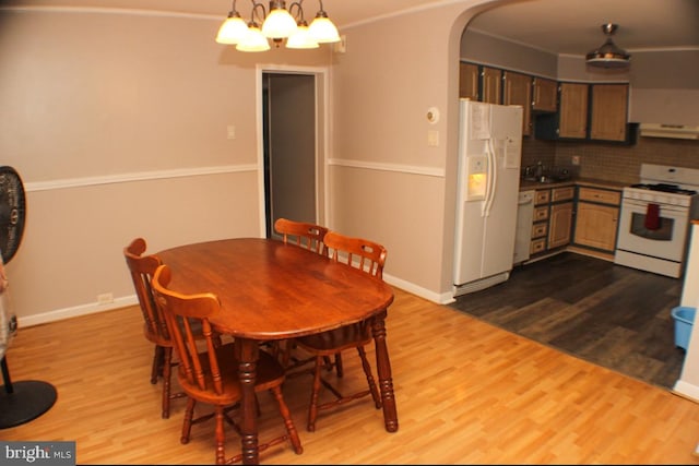 dining room featuring ornamental molding, light wood-type flooring, a chandelier, and sink