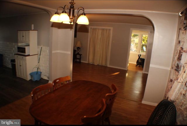 dining area with crown molding, a chandelier, and dark hardwood / wood-style flooring