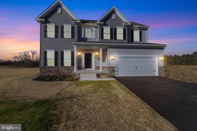 view of front of property featuring aphalt driveway, stone siding, and an attached garage