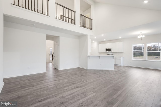 unfurnished living room with recessed lighting, baseboards, wood finished floors, and a chandelier