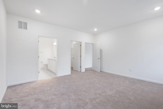 unfurnished bedroom featuring visible vents, baseboards, light colored carpet, recessed lighting, and ensuite bathroom