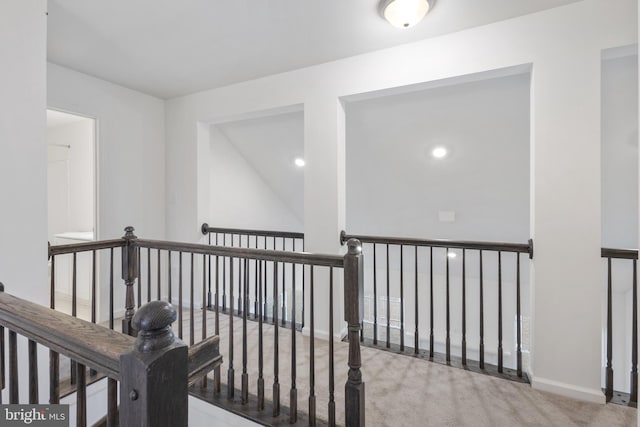 hall with baseboards, carpet floors, and an upstairs landing