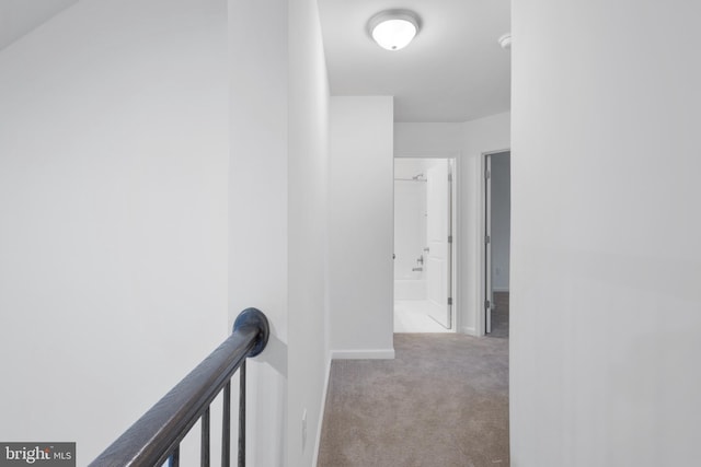 corridor with baseboards, an upstairs landing, and carpet flooring