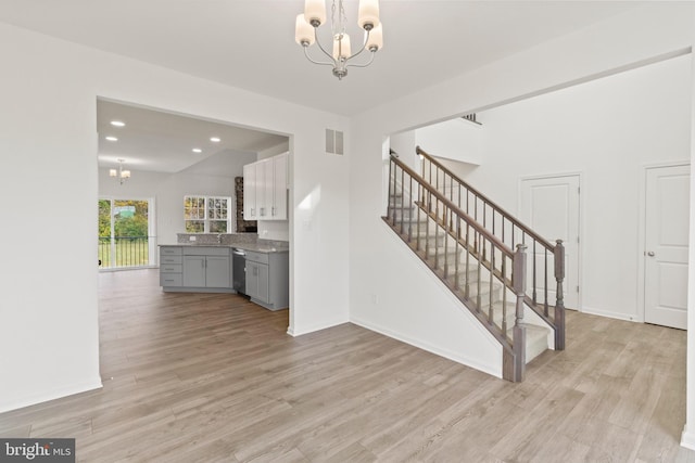 unfurnished living room featuring light wood-type flooring, a notable chandelier, and sink