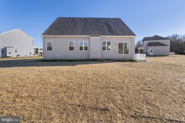 back of property with a yard and roof with shingles