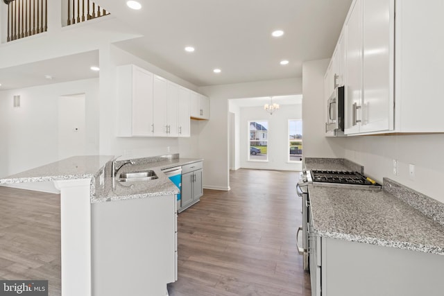 kitchen featuring kitchen peninsula, light hardwood / wood-style floors, white cabinetry, and sink