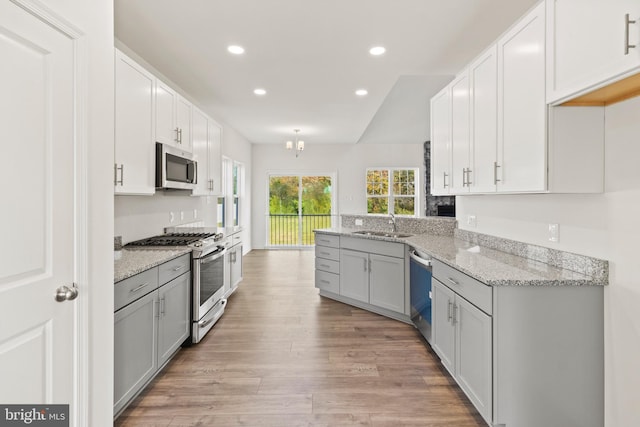 kitchen featuring white cabinetry, sink, stainless steel appliances, light stone counters, and light hardwood / wood-style floors