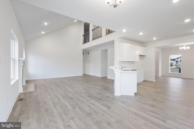 unfurnished living room featuring recessed lighting, baseboards, light wood finished floors, and a chandelier