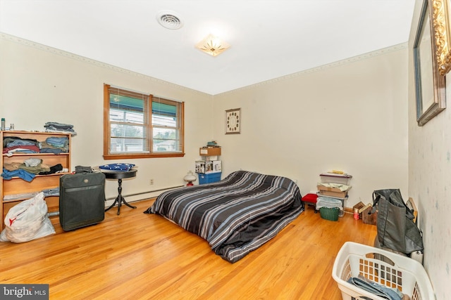 bedroom with baseboard heating and hardwood / wood-style floors