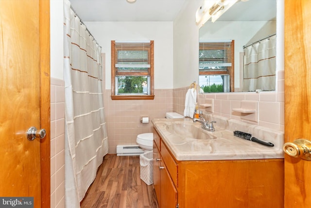 bathroom with vanity, hardwood / wood-style flooring, tile walls, a baseboard radiator, and toilet