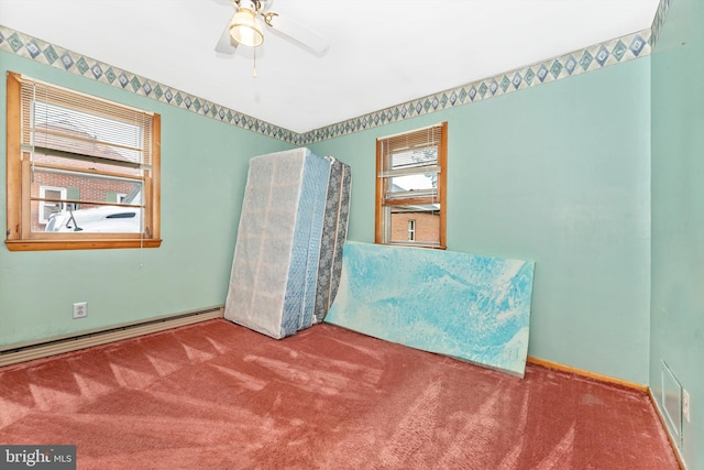 unfurnished bedroom featuring carpet flooring, a baseboard heating unit, multiple windows, and ceiling fan