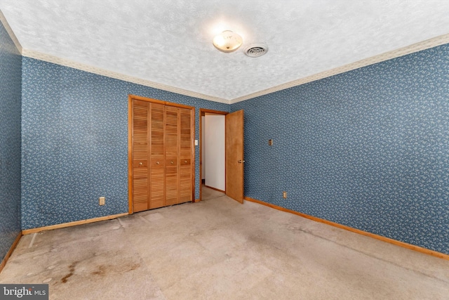 unfurnished bedroom with ornamental molding, carpet floors, a closet, and a textured ceiling