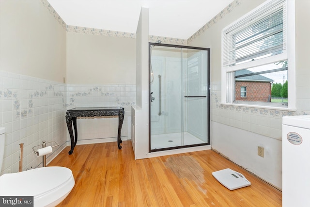 bathroom with an enclosed shower, washer / clothes dryer, hardwood / wood-style flooring, tile walls, and toilet