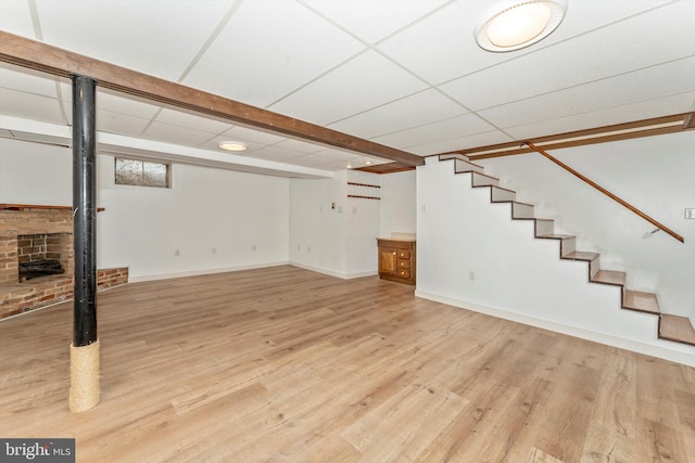 basement with light hardwood / wood-style flooring and a drop ceiling