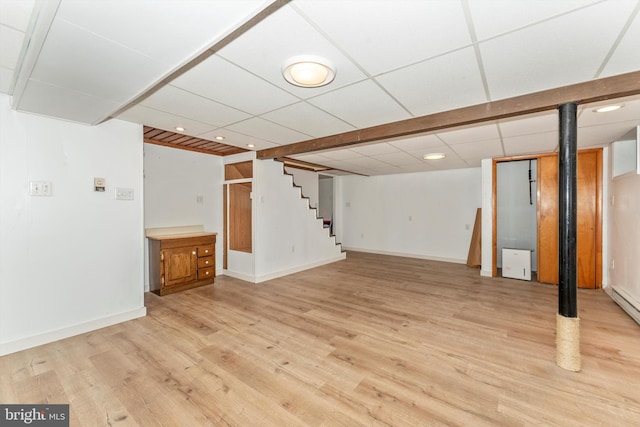 basement with a paneled ceiling and light hardwood / wood-style floors