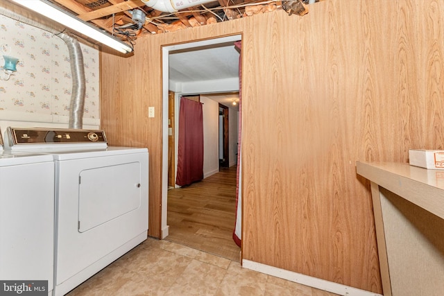 clothes washing area with independent washer and dryer, wood walls, and wood-type flooring