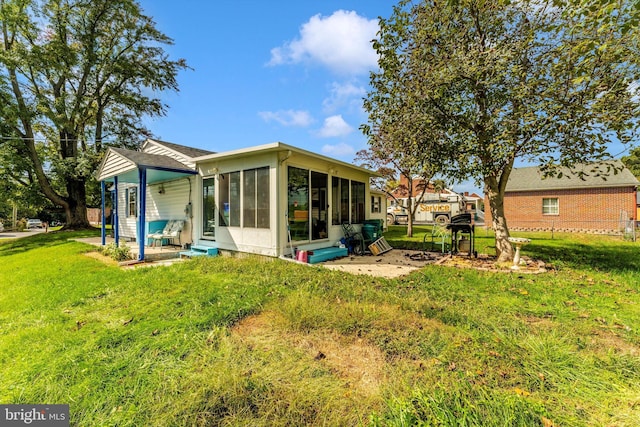 rear view of house featuring a sunroom and a yard