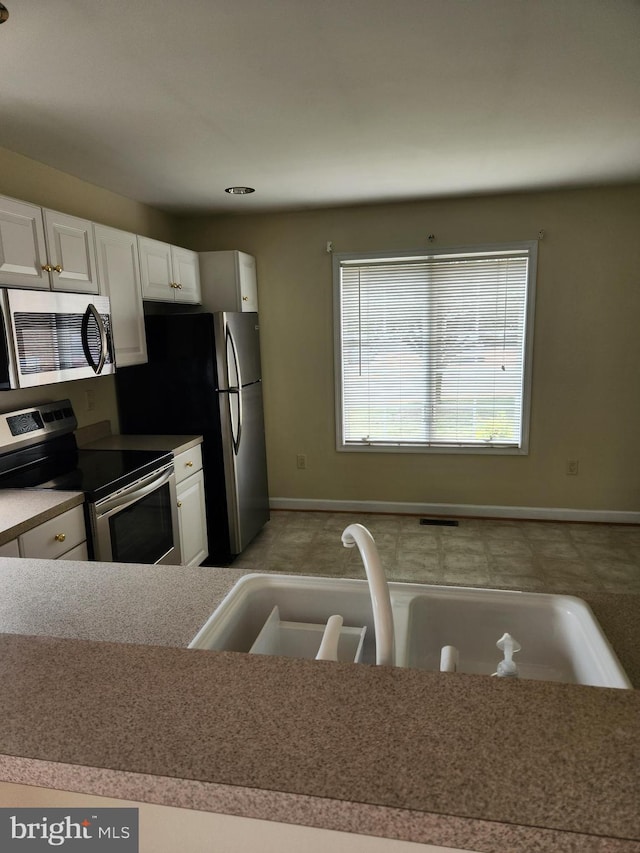 kitchen featuring appliances with stainless steel finishes, sink, and white cabinets