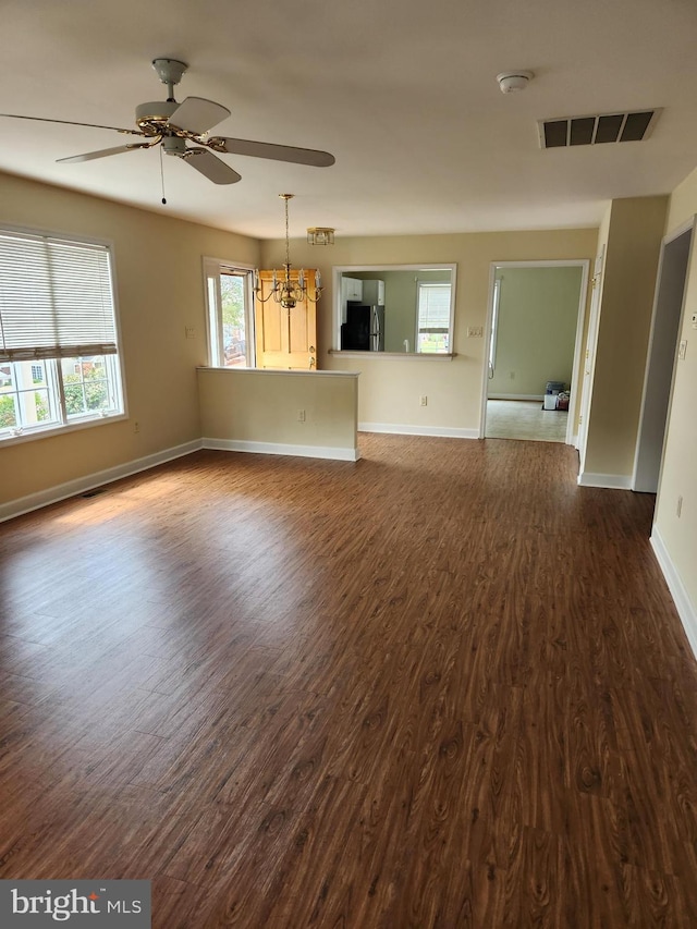 unfurnished living room featuring dark hardwood / wood-style floors and ceiling fan with notable chandelier